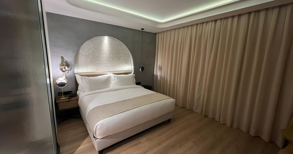 Mur en béton ciré gris dans une chambre d'hôtel, tête de lit arrondie — finition taloché mat